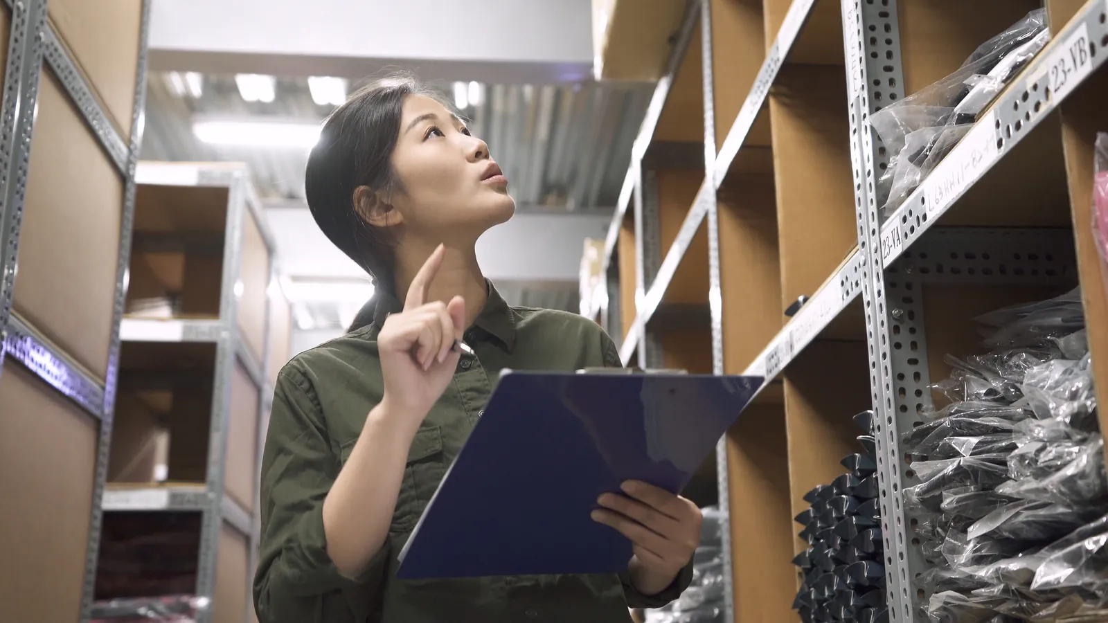 Employee checking stock with a clipboard in a retail stockroom